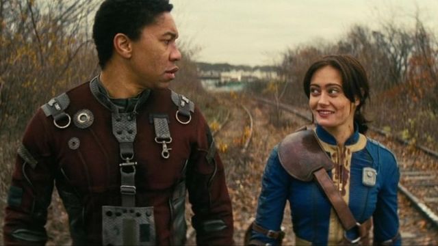 Lucy and Maximus walking along train tracks in the wasteland in the fallout television show.